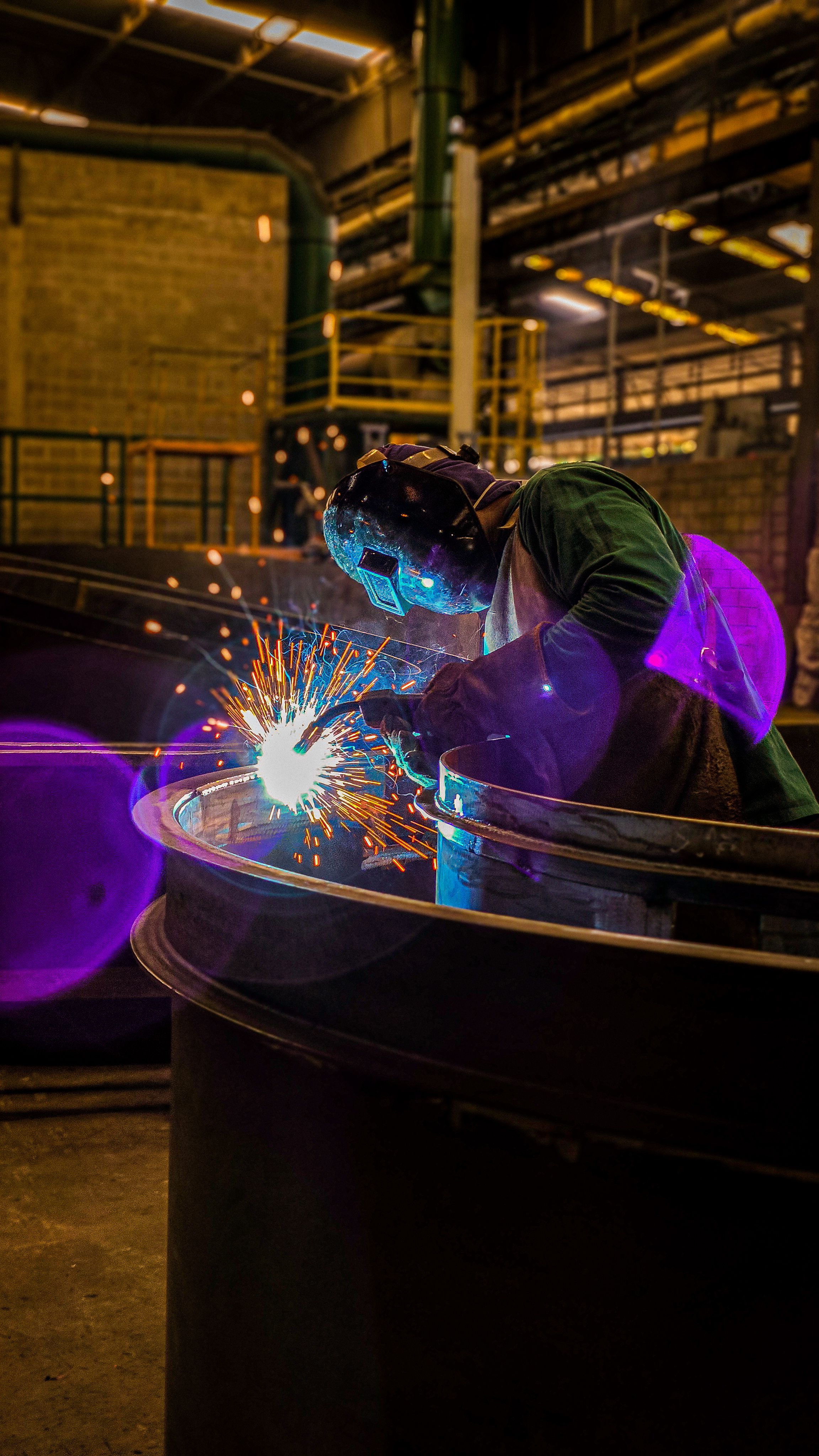 Trabalhador a soldar uma estrutura metálica em ambiente industrial